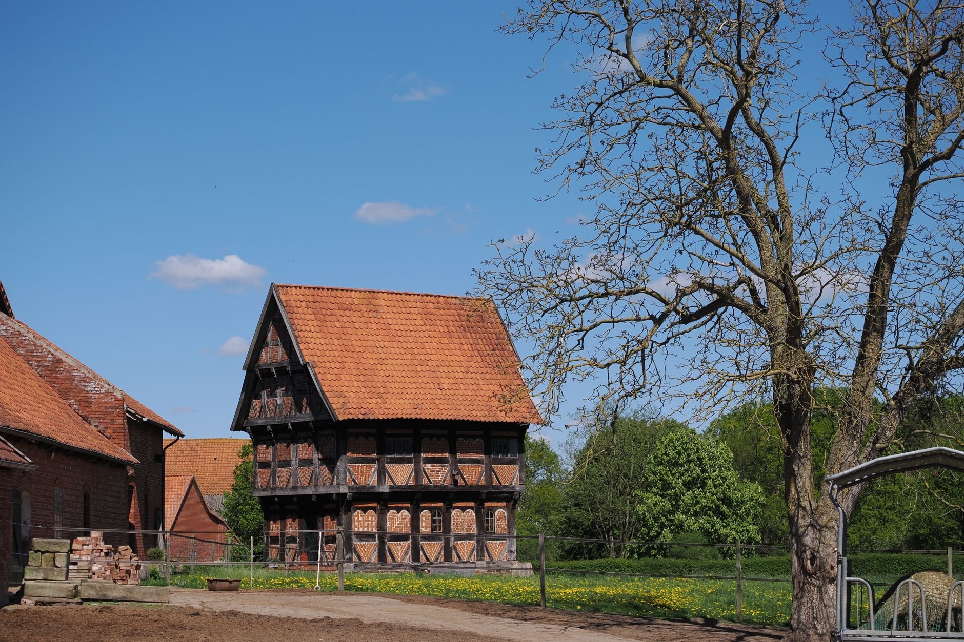 A timber-framed house with a red-tiled roof in a countryside setting.
